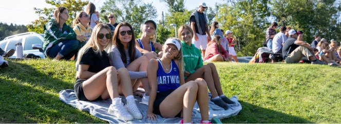 students sit on blankets in the grass